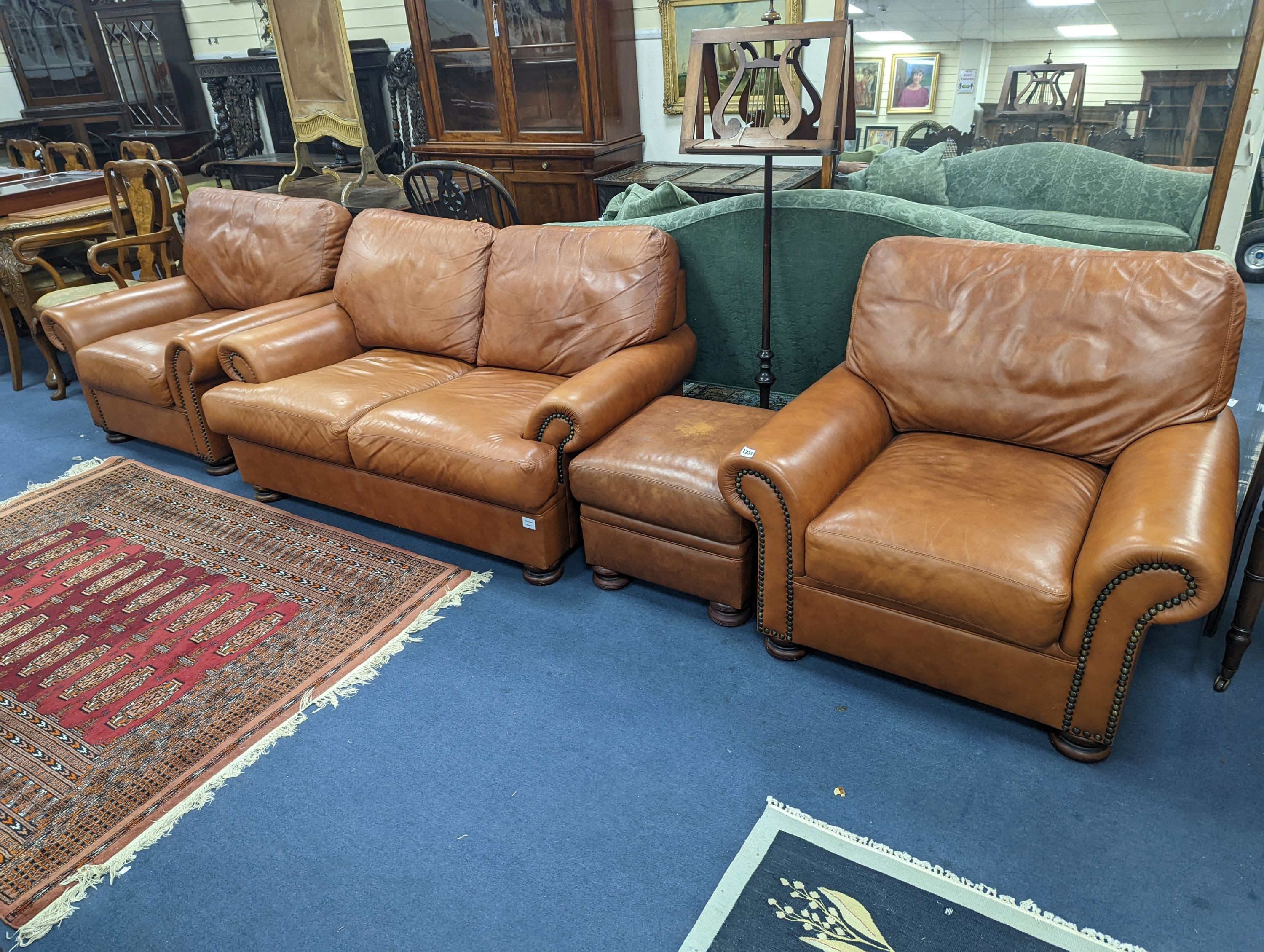 A contemporary tan leather three piece suite and footstool, settee length 150cm, depth 90cm, height 84cm